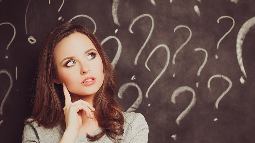 Woman in front of question marks on blackboard